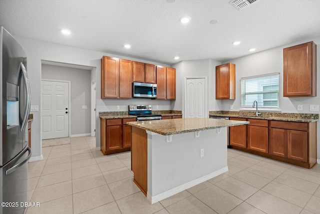 kitchen featuring light tile patterned flooring, light stone counters, a kitchen breakfast bar, a kitchen island, and stainless steel appliances