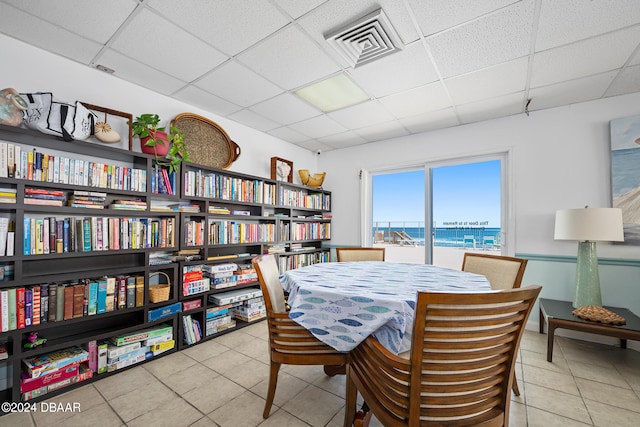 dining space featuring a paneled ceiling, a water view, and tile patterned floors