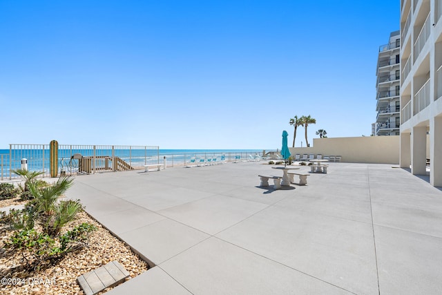 view of patio / terrace featuring a water view and a beach view