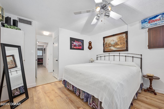 bedroom featuring a textured ceiling, light wood-type flooring, and ceiling fan