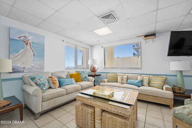 living room featuring a paneled ceiling and light tile patterned flooring