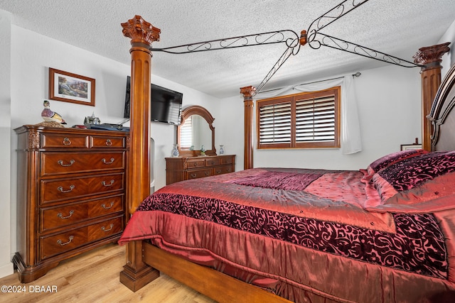 bedroom with light wood-type flooring and a textured ceiling