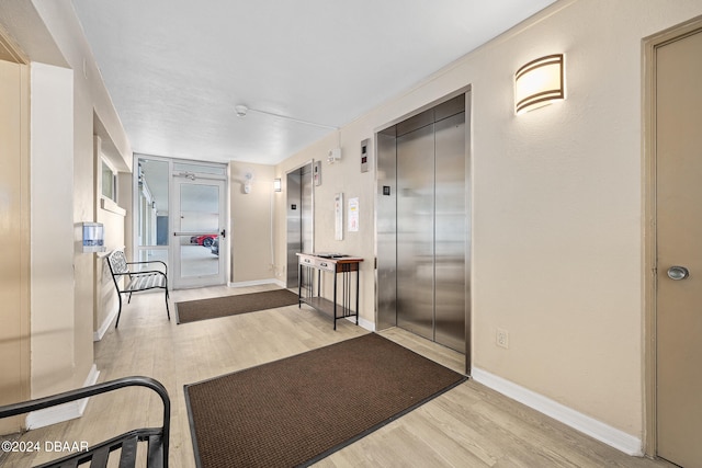 hall with elevator and light wood-type flooring