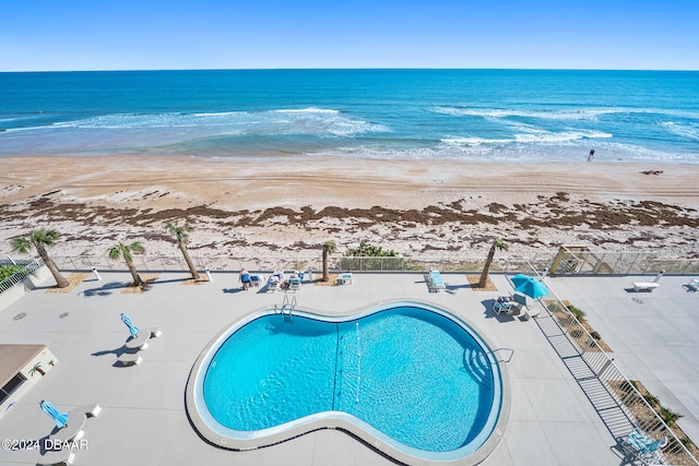 view of swimming pool with a view of the beach, a water view, and a patio