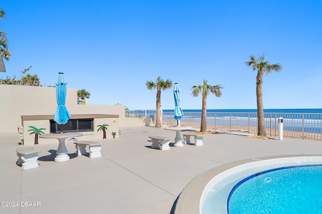 view of pool with a water view and a patio