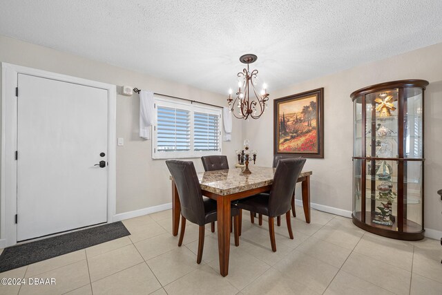 tiled dining space featuring a textured ceiling and a notable chandelier