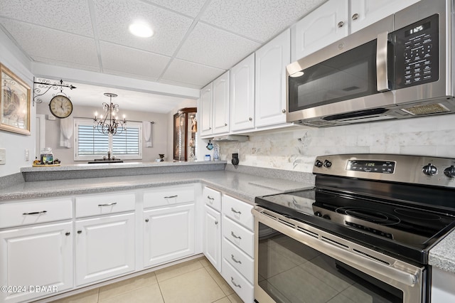 kitchen with white cabinetry, appliances with stainless steel finishes, a paneled ceiling, and a chandelier