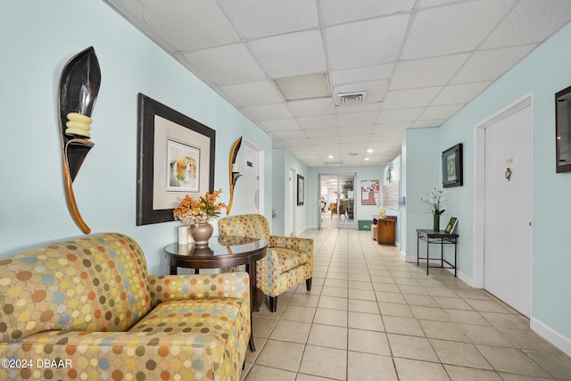 living room with a drop ceiling and light tile patterned floors