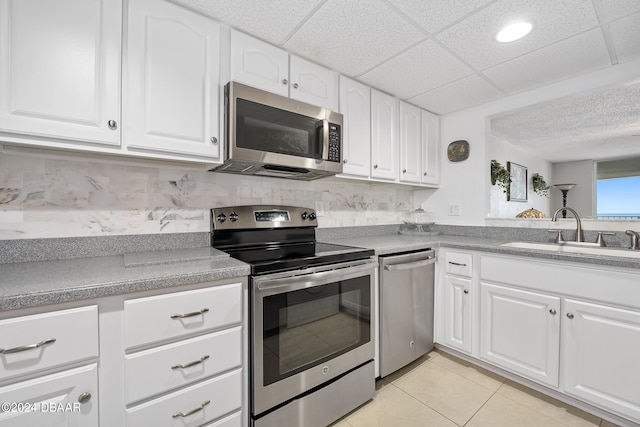 kitchen with white cabinetry, sink, a paneled ceiling, appliances with stainless steel finishes, and tasteful backsplash