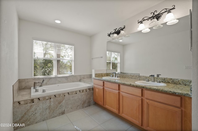 bathroom with tile patterned flooring, vanity, a healthy amount of sunlight, and a relaxing tiled tub