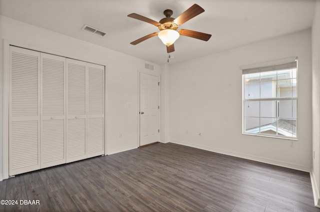 unfurnished bedroom featuring ceiling fan, a closet, and dark wood-type flooring