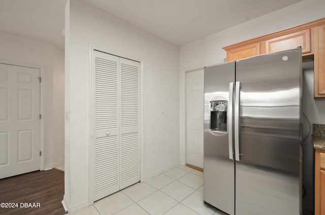 kitchen with stainless steel fridge, light brown cabinetry, and light tile patterned floors