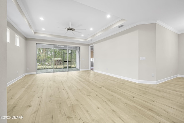 unfurnished living room with ornamental molding, ceiling fan, a tray ceiling, and light wood-type flooring