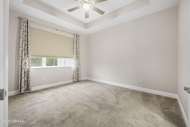 carpeted empty room with ceiling fan and a tray ceiling