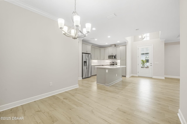 kitchen with decorative light fixtures, a center island with sink, a notable chandelier, light hardwood / wood-style floors, and appliances with stainless steel finishes