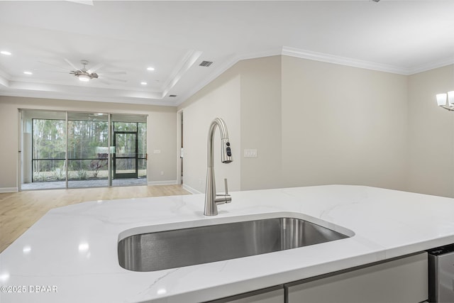 kitchen featuring sink, light stone counters, a raised ceiling, ceiling fan, and light hardwood / wood-style floors