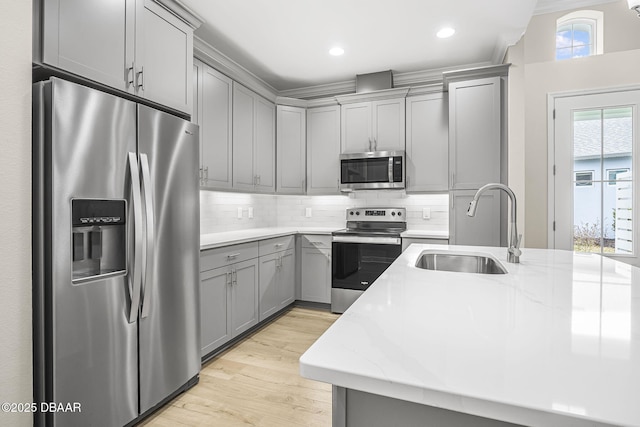 kitchen featuring stainless steel appliances, sink, light stone counters, backsplash, and gray cabinetry