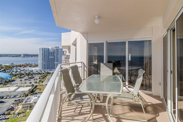 balcony featuring a view of city, outdoor dining area, and a water view