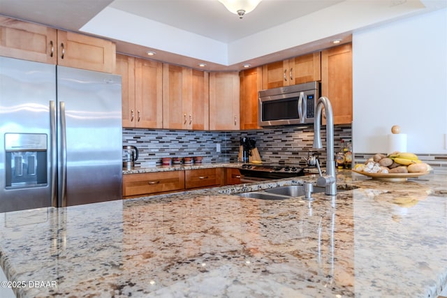 kitchen featuring light stone counters, backsplash, stainless steel appliances, a sink, and recessed lighting