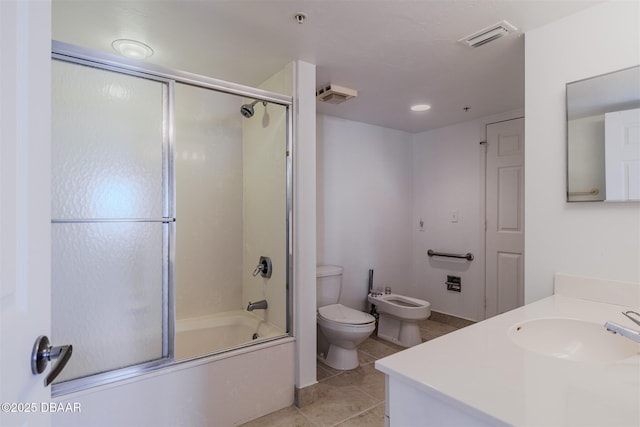 bathroom with tile patterned flooring, toilet, vanity, combined bath / shower with glass door, and a bidet