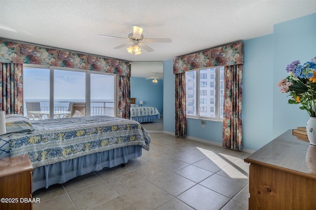 bedroom featuring light tile patterned floors, a ceiling fan, baseboards, and a textured ceiling