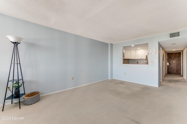 unfurnished living room with light carpet and a textured ceiling