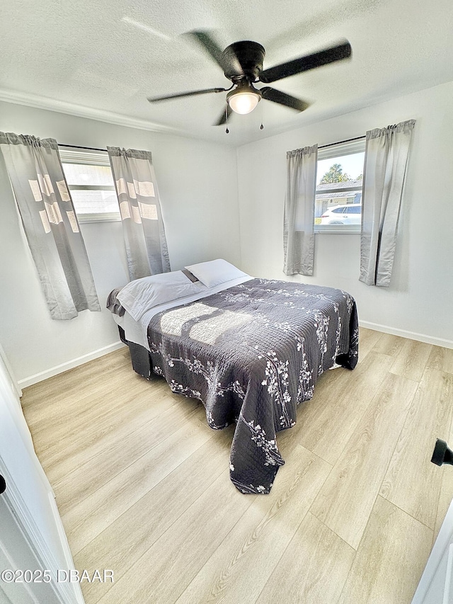 bedroom featuring multiple windows, hardwood / wood-style floors, a textured ceiling, and ceiling fan