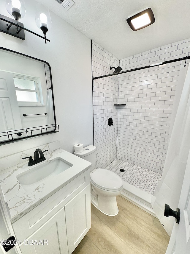 bathroom featuring curtained shower, toilet, wood-type flooring, a textured ceiling, and vanity