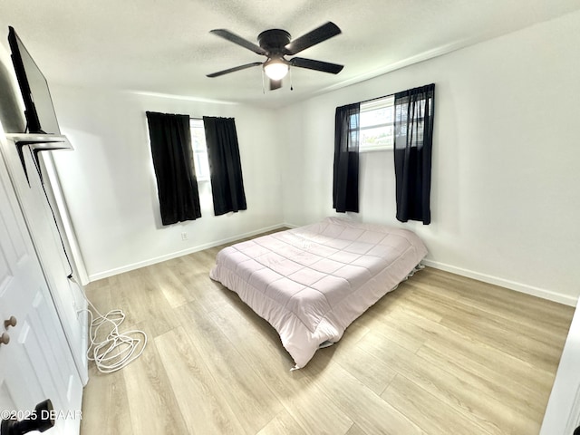 bedroom with light hardwood / wood-style flooring, ceiling fan, and a textured ceiling