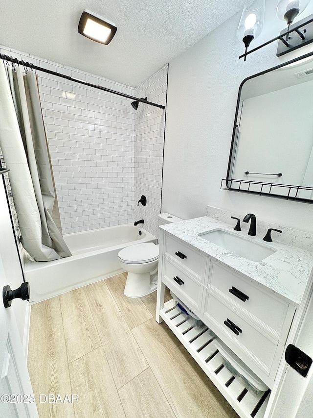 full bathroom featuring shower / tub combo, toilet, wood-type flooring, a textured ceiling, and vanity