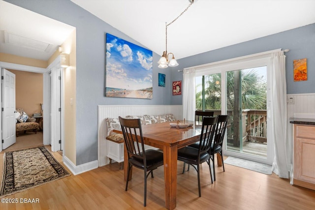 dining area featuring light hardwood / wood-style floors, vaulted ceiling, and an inviting chandelier