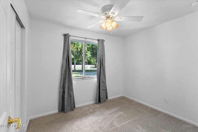 carpeted spare room with ceiling fan and a textured ceiling