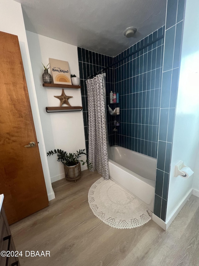 bathroom with hardwood / wood-style floors, a textured ceiling, and shower / bath combo with shower curtain