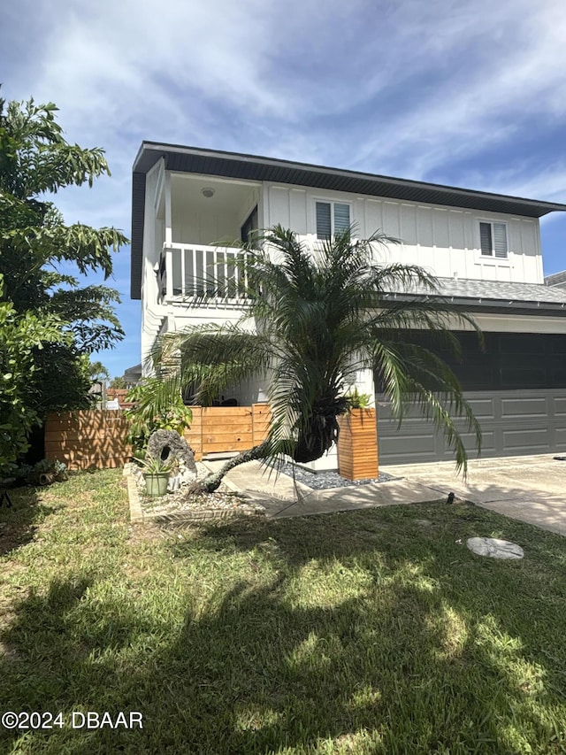 view of front facade with a front yard, a balcony, and a garage