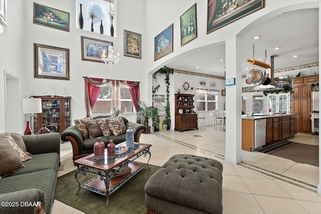 living room with light tile patterned flooring, sink, an inviting chandelier, and a high ceiling