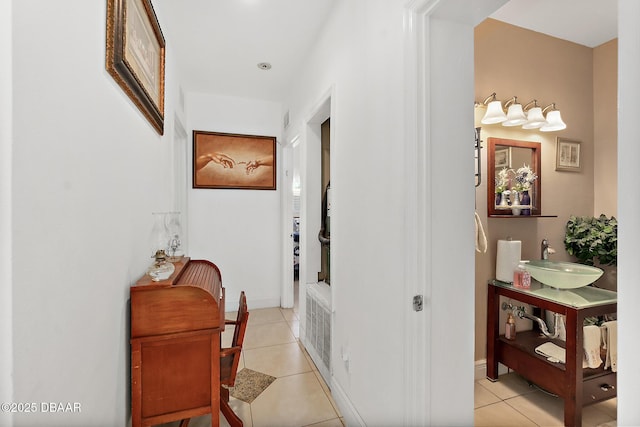 hall featuring light tile patterned flooring, sink, and radiator