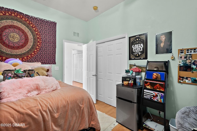 bedroom featuring light hardwood / wood-style floors, stainless steel refrigerator, and a closet