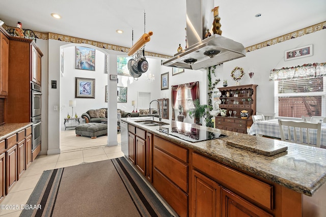 kitchen with sink, a center island with sink, stainless steel appliances, island exhaust hood, and light tile patterned flooring