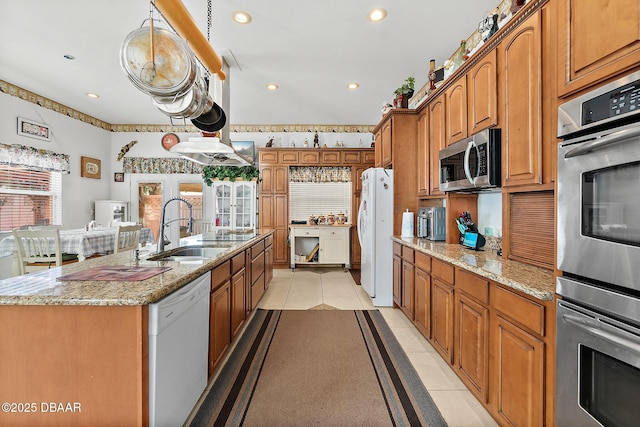 kitchen featuring stainless steel appliances, a kitchen island with sink, sink, and light tile patterned floors