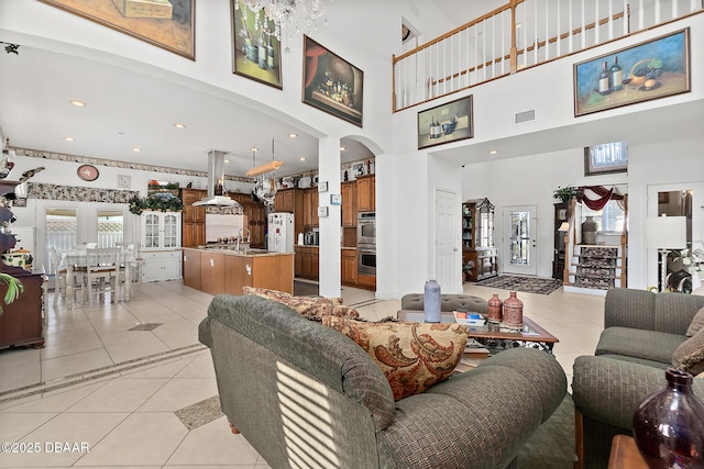 living room with sink, a towering ceiling, and light tile patterned floors