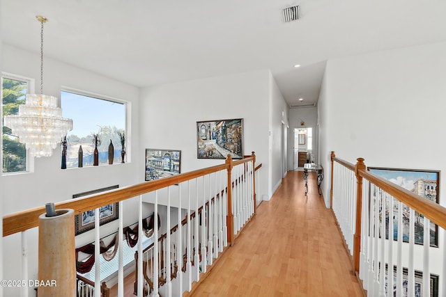 hall featuring an inviting chandelier and light hardwood / wood-style floors