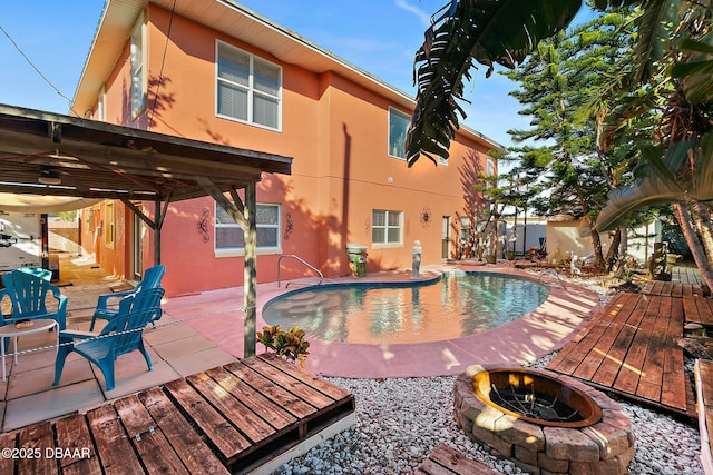 view of swimming pool with a wooden deck, a fire pit, and a patio area