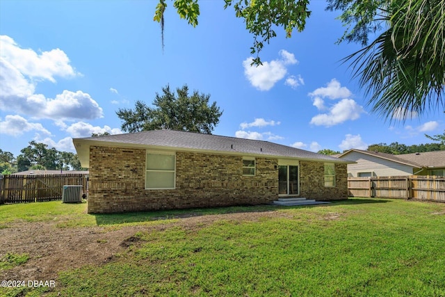 rear view of house featuring central air condition unit and a yard