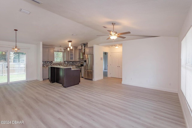 kitchen featuring light hardwood / wood-style floors, lofted ceiling, a kitchen island, pendant lighting, and appliances with stainless steel finishes