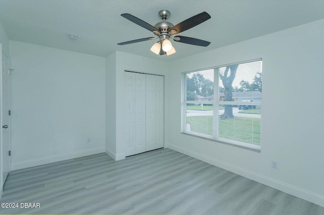 unfurnished bedroom featuring light hardwood / wood-style flooring, ceiling fan, and a closet