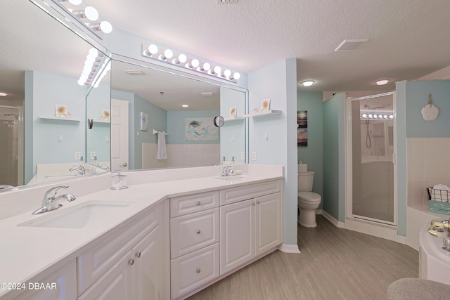 bathroom featuring vanity, wood-type flooring, a shower with door, and a textured ceiling