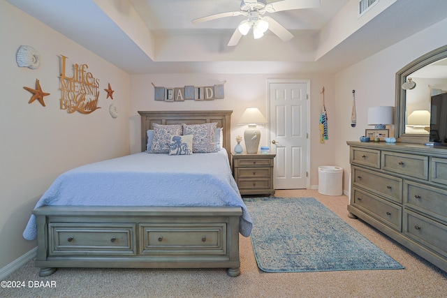 bedroom featuring light carpet, ceiling fan, and a tray ceiling