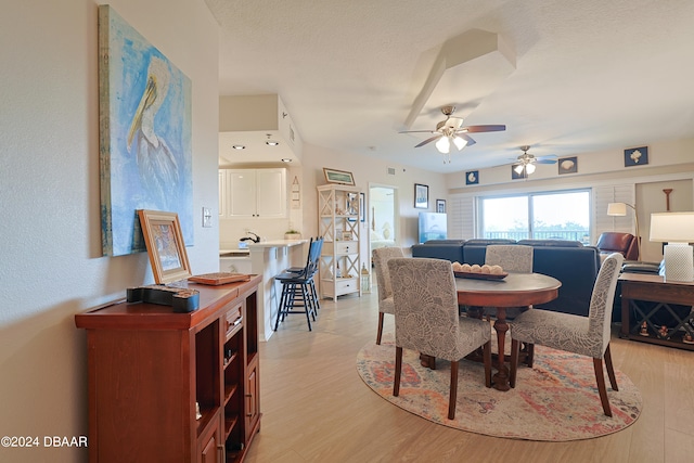 dining area featuring a textured ceiling, light wood-type flooring, and ceiling fan