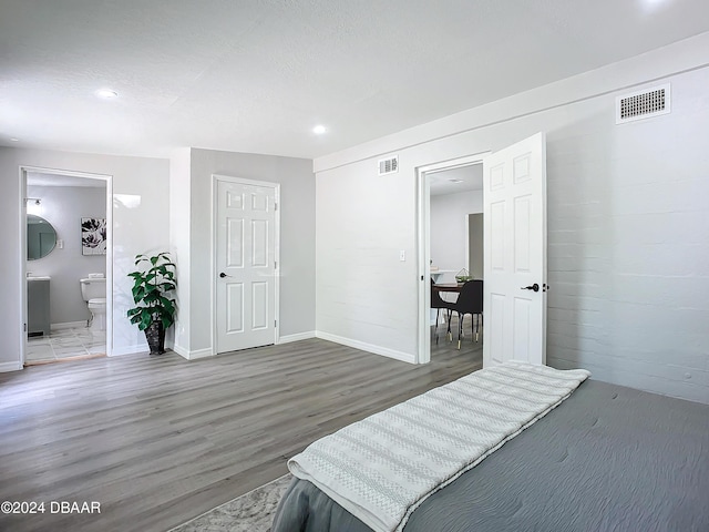 bedroom featuring a textured ceiling, dark wood-type flooring, and connected bathroom