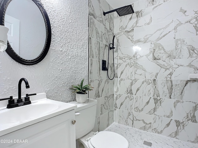 bathroom with a tile shower, vanity, and toilet